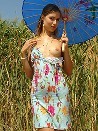 Girl in a light dress strolling outdoors, hiding from the sun under the sunshade and stripping pictures